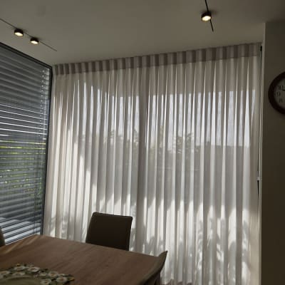 וילון לבן תלוי בחדר מואר עם שולחן עץ וכיסאות