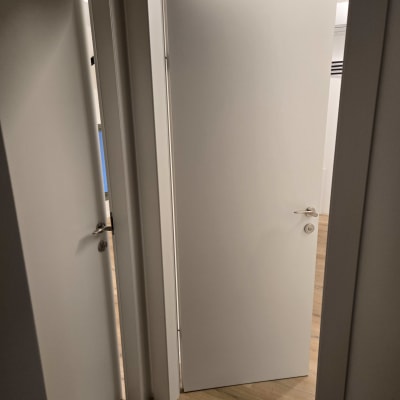 שתי דלתות לבנות פתוחות חלקית עם ידיות כסופות