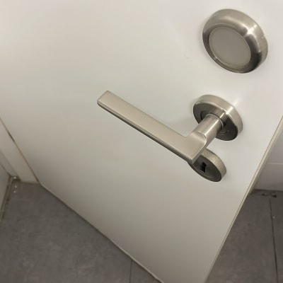 ידית דלת מתכתית על דלת לבנה