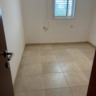 חדר ריק עם רצפת אריחים וחלון עם תריסים