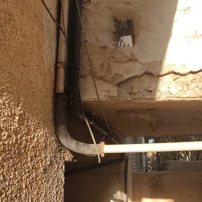 צנרת חיצונית עם קיר מתקלף וחור בקיר