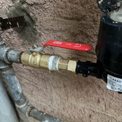 שסתום וצינור מתכת על קיר טיח