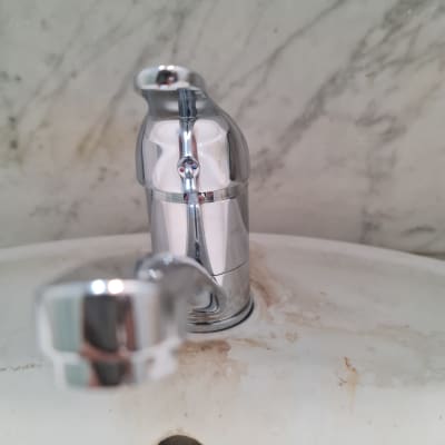 ברז כרום מותקן על כיור עם כתמי חלודה