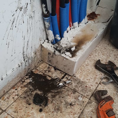 צינורות מים עם לכלוך וכלי עבודה על הרצפה