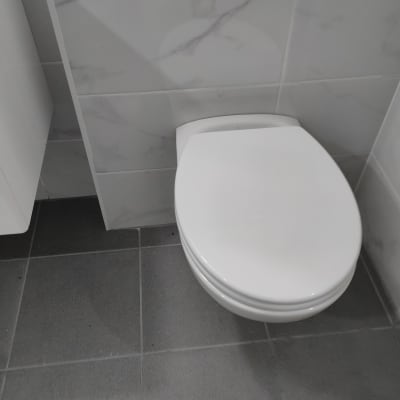 אסלה לבנה על רצפת אריחים אפורה בחדר אמבטיה