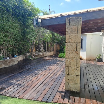 דק עץ בגינה עם צמחייה מסביב ועמוד אבן