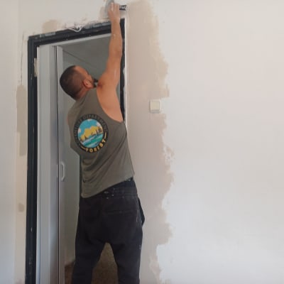 אדם צובע קיר ליד דלת