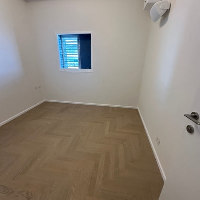 חדר עם רצפת פרקט ודלת לבנה