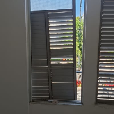 תריסים שבורים בחלון עם נוף חיצוני