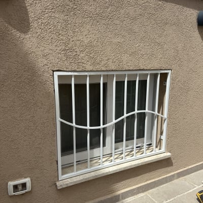 חלון עם סורגים לבנים על קיר חום