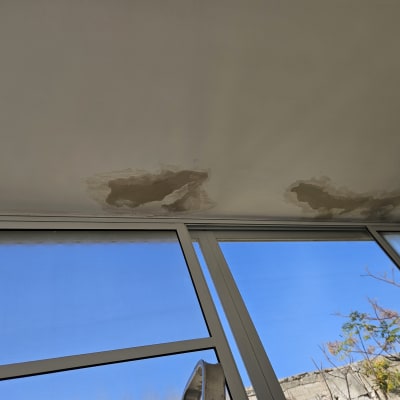 חלונות עם תריסים סגורים למחצה, שמיים כחולים ברקע.