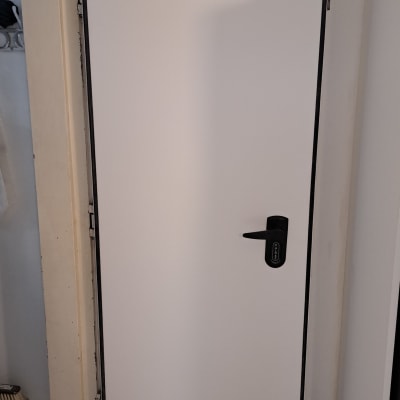 דלת לבנה עם ידית שחורה במסגרת כהה