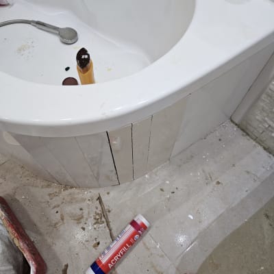 אמבטיה עם כלי עבודה וחומרי איטום על הרצפה