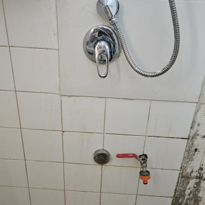 ברז מים ומקלחת על קיר אריחים