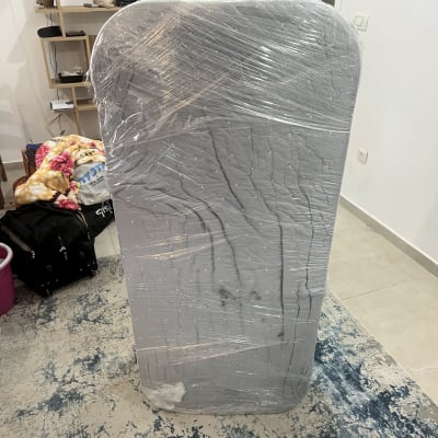 אדם מחזיק מזרן עטוף בניילון בבית