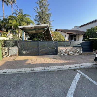 פרגולה מאלומיניום בחצר עם גדר מתכת