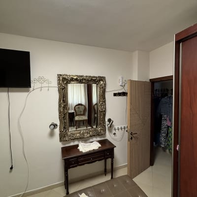 מראה עם מסגרת מעוטרת, שולחן קטן, כיסא ברקע