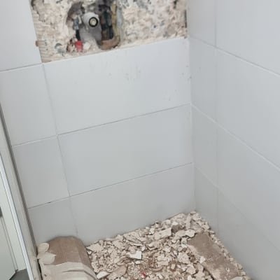 קיר פתוח עם צנרת חשופה ופסולת בנייה על הרצפה