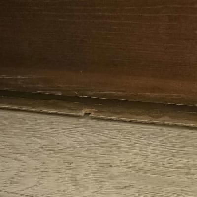 רצפת עץ עם לוח עץ שבור מתחת לרהיט