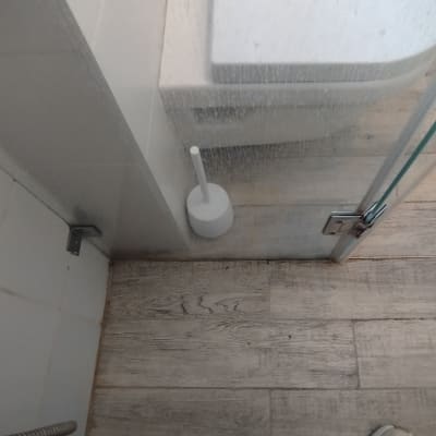 מקלחון עם דלת זכוכית ומברשת ניקוי לבנה