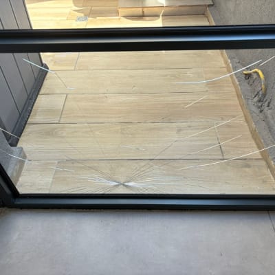 זכוכית שבורה במסגרת מתכת על רצפת עץ