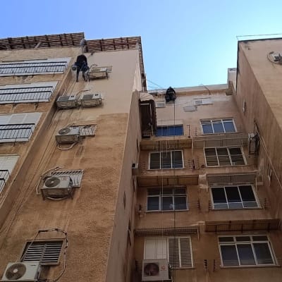 עובדים בגובה על בניין עם מזגנים