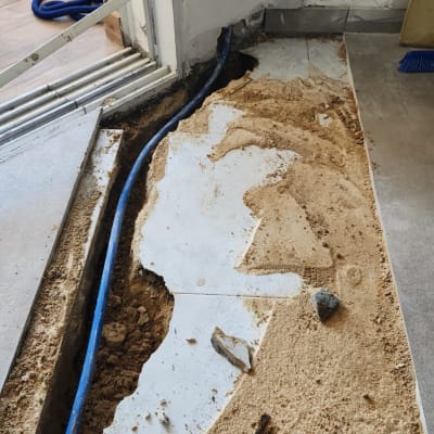 חפירה ברצפה עם צינור כחול וכלי עבודה