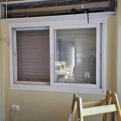 תריסים וחלון עם סולם עץ בחדר פנימי