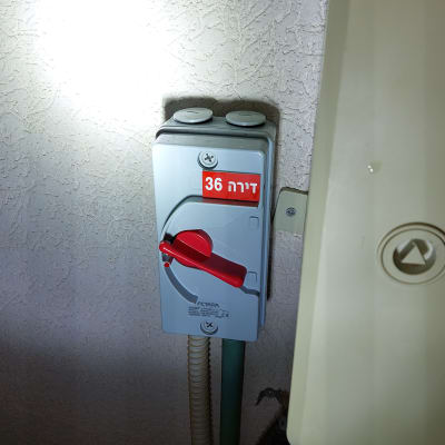 מתג חשמלי עם ידית אדומה על קיר