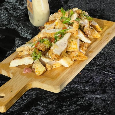 חזה עוף פרוס על קרש חיתוך עם רוטב בצד