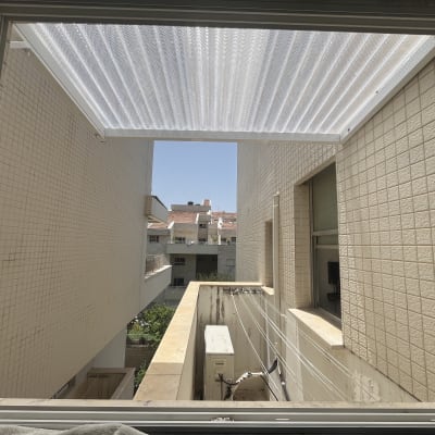 סוכך לבן מותקן בין שני קירות חיצוניים