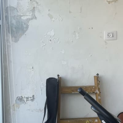 קיר מתקלף עם סולם עץ וציוד ניקוי