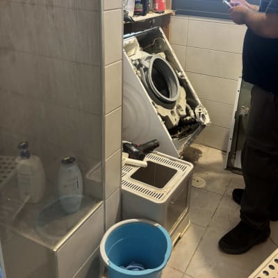 אדם מתקן מכונת כביסה בחדר אמבטיה