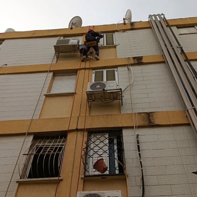 עובד בגובה מתקין מזגן על בניין