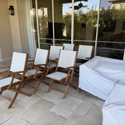כיסאות עץ מתקפלים עם מושבים לבנים על מרפסת