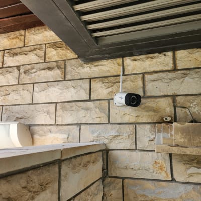 מצלמת אבטחה מותקנת על קיר אבן מתחת לגג
