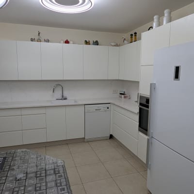 מטבח מודרני עם ארונות לבנים ומקרר גדול