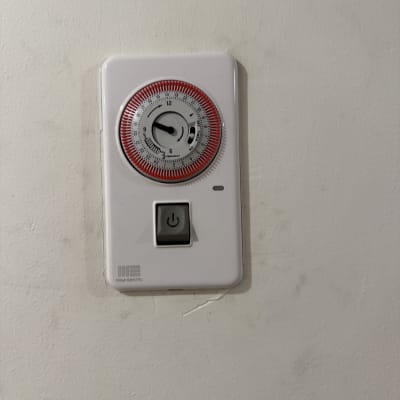 טיימר חשמלי עם כפתור הפעלה על קיר לבן