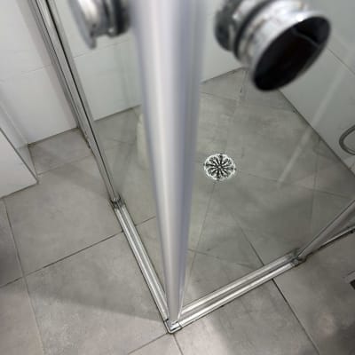 מקלחון זכוכית עם רצפת אריחים וניקוז