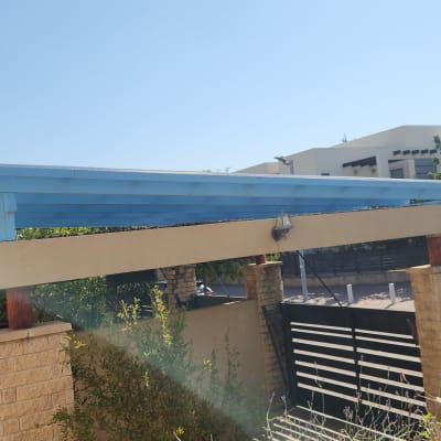 פרגולה מעץ צבועה בכחול עם עמודי אבן