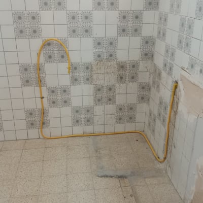 קיר עם אריחים וצינור גז צהוב