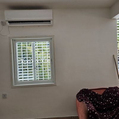חלון עם תריסים ומזגן על קיר לבן