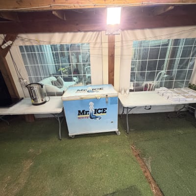 ציוד להשכרת אירועים כולל מקרר ומיחם על שולחנות מתקפלים