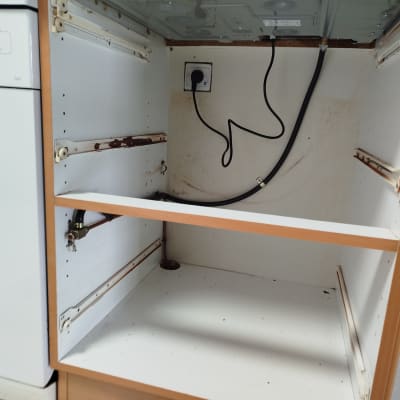 ארון מטבח פתוח עם חיבורי גז וצינור חשמל