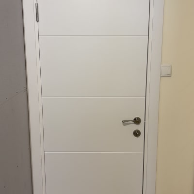 דלת לבנה עם ידית כסופה מותקנת בקיר