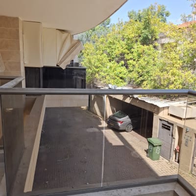 מעקה זכוכית עם נוף לחצר ומכונית חונה