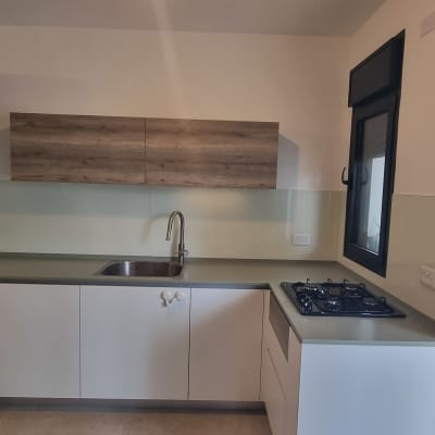 מטבח עם חיפוי זכוכית מעל השיש והכיור