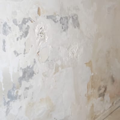 קיר עם טיח מתקלף ותיקון בטון בתחתית