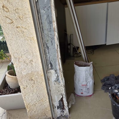 עבודת תיקון מסגרת אלומיניום ליד קיר אבן