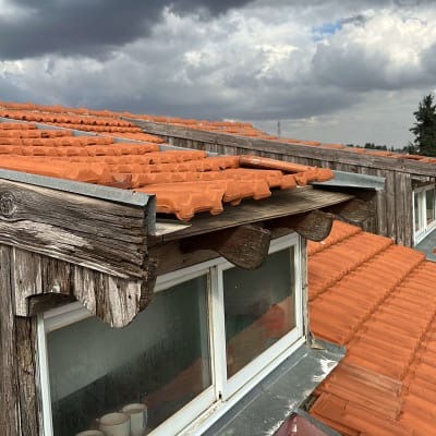 גג רעפים עם חלון עץ תחת שמיים מעוננים